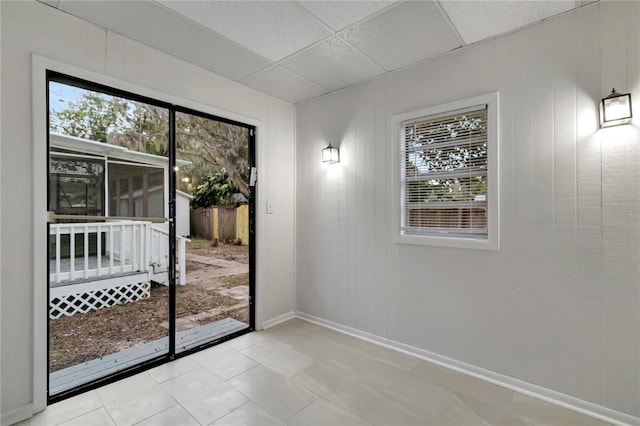 doorway to outside featuring a paneled ceiling, plenty of natural light, and light tile patterned floors