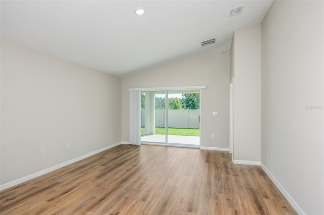 spare room featuring light wood-type flooring, lofted ceiling, visible vents, and baseboards