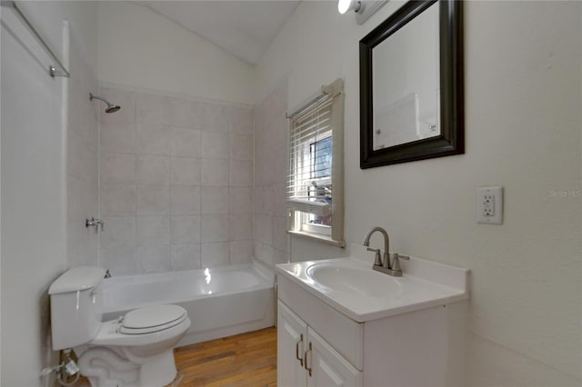 full bathroom with vanity, hardwood / wood-style flooring, toilet, tiled shower / bath, and lofted ceiling