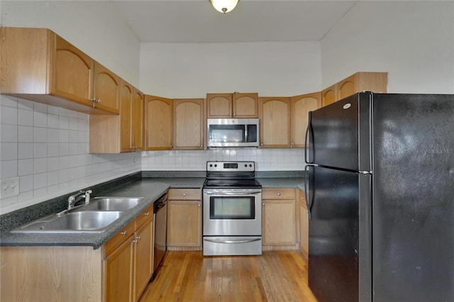 kitchen with sink, light brown cabinets, light hardwood / wood-style flooring, decorative backsplash, and appliances with stainless steel finishes