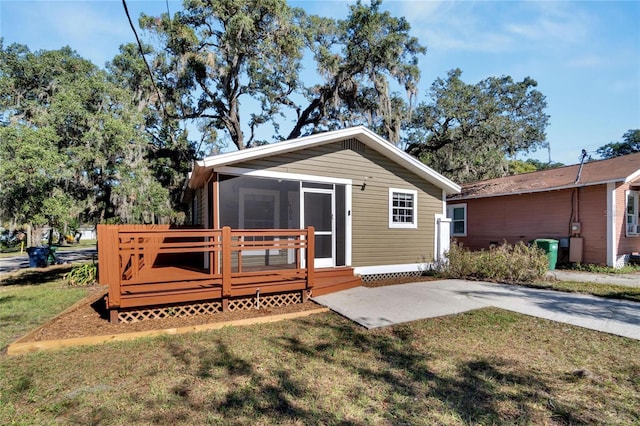 rear view of house featuring a sunroom, a deck, and a yard