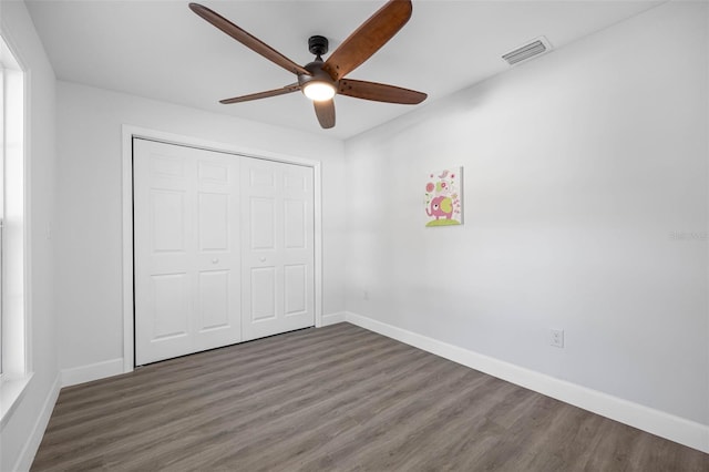 unfurnished bedroom featuring ceiling fan, a closet, and dark wood-type flooring