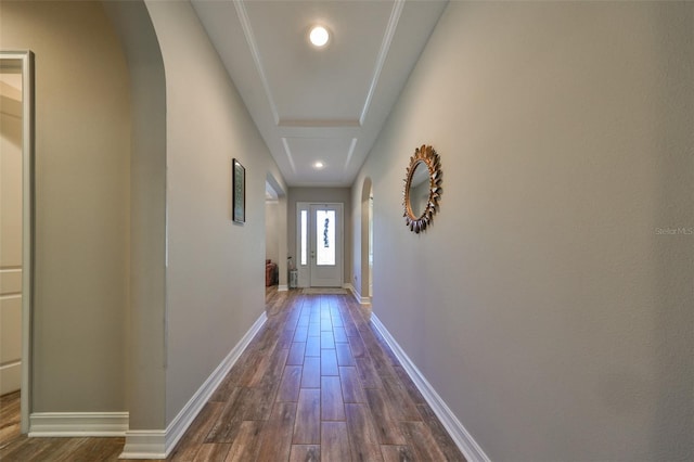 corridor featuring a tray ceiling and dark wood-type flooring