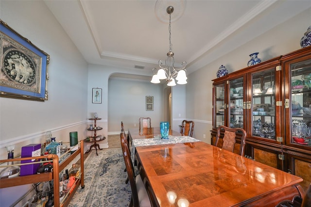 dining space with a tray ceiling, a chandelier, and hardwood / wood-style flooring