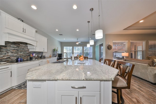 kitchen featuring a breakfast bar area, a large island, sink, and light wood-type flooring