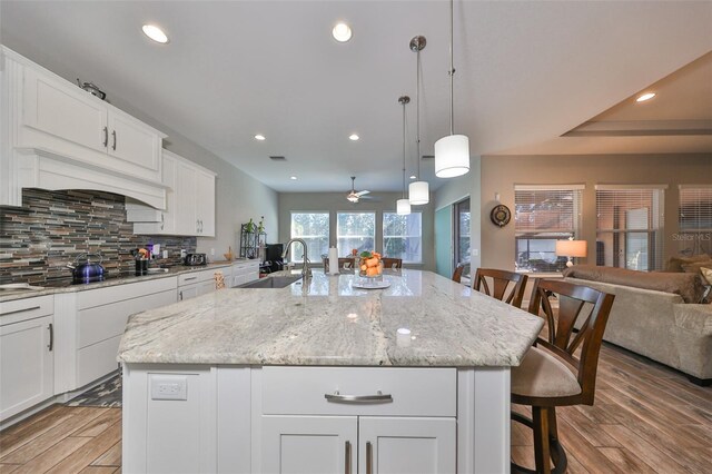 13230 Fawn Lily Dr, Riverview, FL 33579 - kitchen with a sink, open floor plan, tasteful backsplash, light wood finished floors, and a kitchen breakfast bar