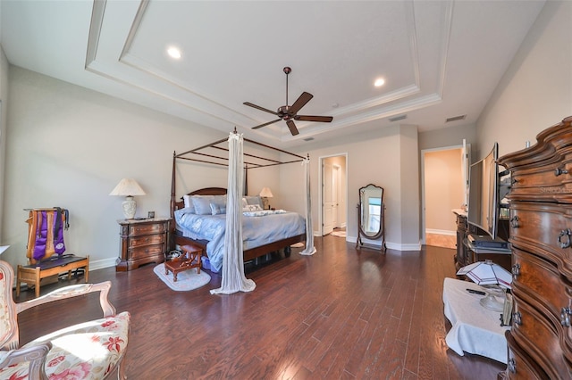 bedroom with a raised ceiling, ceiling fan, and dark wood-type flooring