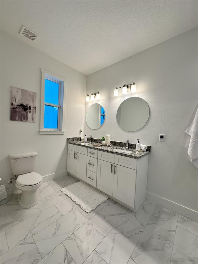 bathroom with a textured ceiling, vanity, and toilet