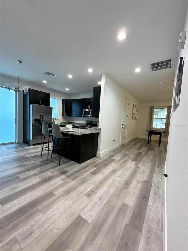 3208 Deleuil Ave, Tampa, FL 33610 - kitchen with stainless steel appliances, a center island, recessed lighting, dark cabinetry, and light wood-type flooring