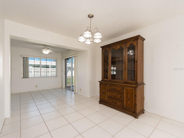 unfurnished dining area with ceiling fan with notable chandelier, a textured ceiling, and light tile patterned flooring