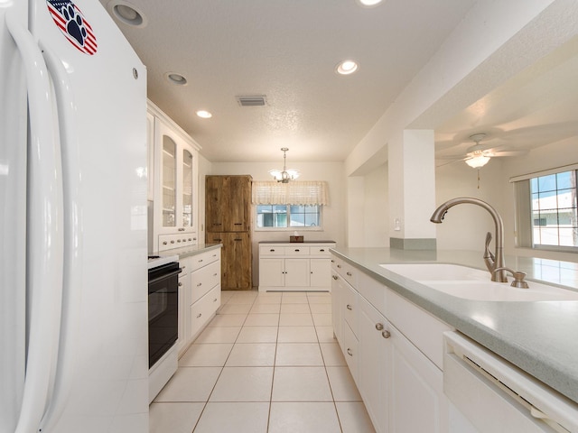 kitchen featuring sink, white appliances, hanging light fixtures, white cabinets, and ceiling fan with notable chandelier