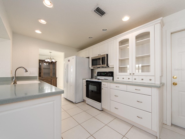 kitchen with white fridge, electric range oven, sink, an inviting chandelier, and white cabinetry