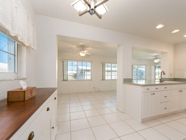 kitchen featuring ceiling fan, light tile patterned floors, white cabinets, and sink