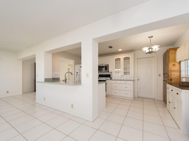 kitchen featuring kitchen peninsula, light tile patterned flooring, white fridge with ice dispenser, a chandelier, and sink