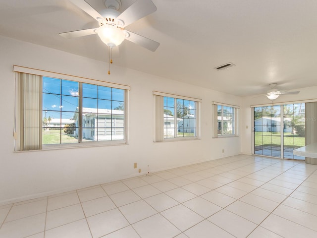 tiled empty room featuring ceiling fan and a healthy amount of sunlight