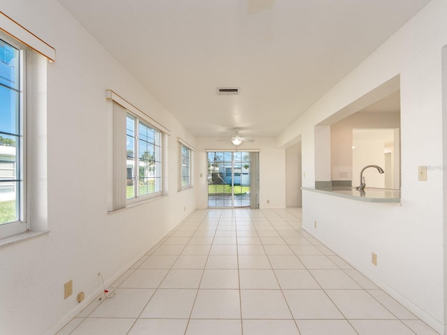 hall with sink, light tile patterned floors, and a healthy amount of sunlight