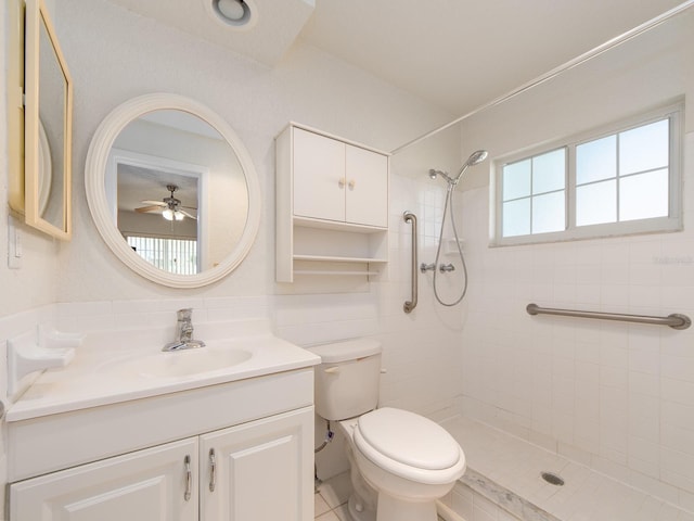 bathroom with tile patterned flooring, vanity, toilet, ceiling fan, and a tile shower