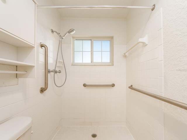 bathroom with toilet and a tile shower