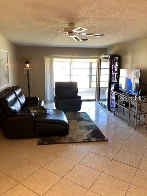 tiled living room featuring ceiling fan and a textured ceiling