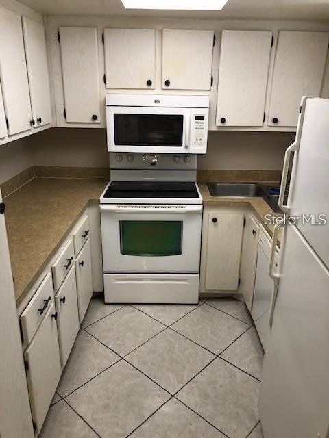 kitchen featuring white cabinets, white appliances, and light tile patterned flooring