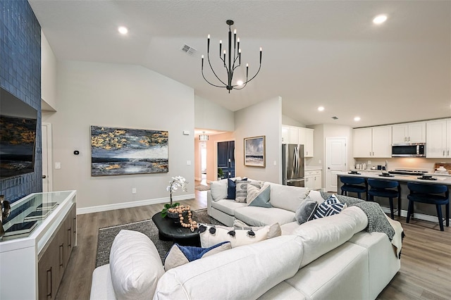 living room with wood-type flooring, lofted ceiling, and a notable chandelier