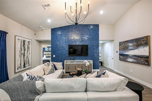 living room with vaulted ceiling, a textured ceiling, hardwood / wood-style flooring, and a notable chandelier