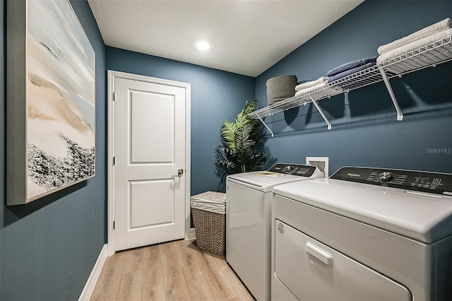 clothes washing area with washer and clothes dryer and light hardwood / wood-style flooring