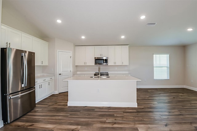 kitchen with stainless steel appliances, white cabinetry, light countertops, an island with sink, and dark wood finished floors