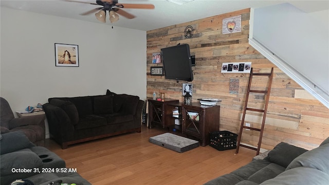 living room featuring hardwood / wood-style floors, ceiling fan, and wood walls