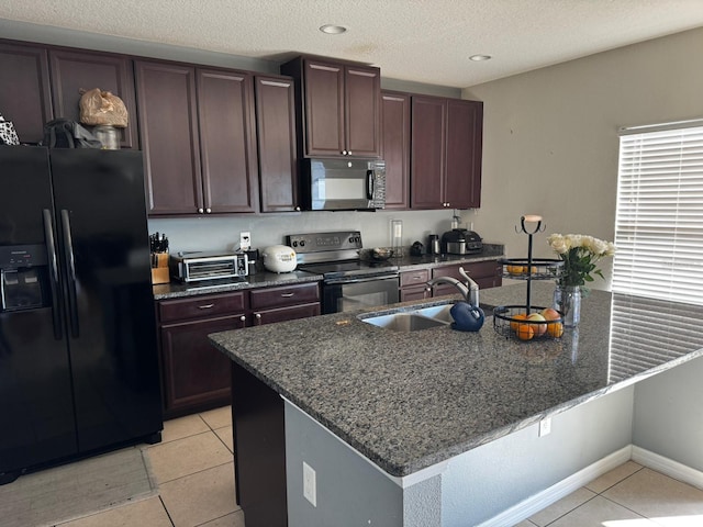 kitchen with a center island with sink, light tile patterned flooring, sink, and stainless steel appliances