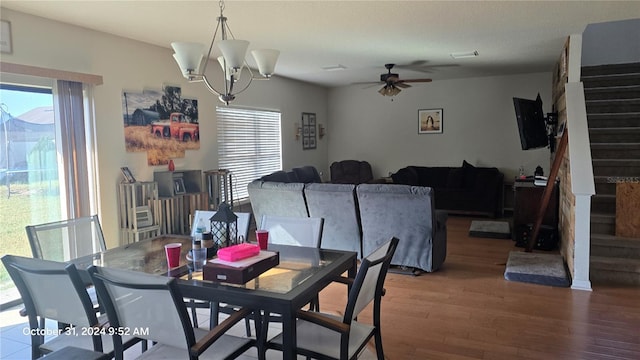 dining space with hardwood / wood-style flooring, ceiling fan with notable chandelier, and a healthy amount of sunlight