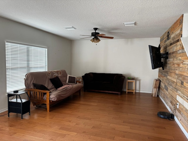 living room featuring ceiling fan, light hardwood / wood-style flooring, and a textured ceiling