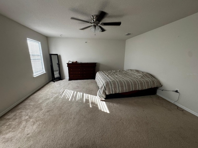 carpeted bedroom featuring ceiling fan and a textured ceiling