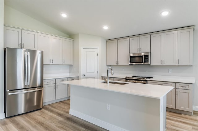 kitchen with light wood finished floors, stainless steel appliances, light countertops, a sink, and recessed lighting