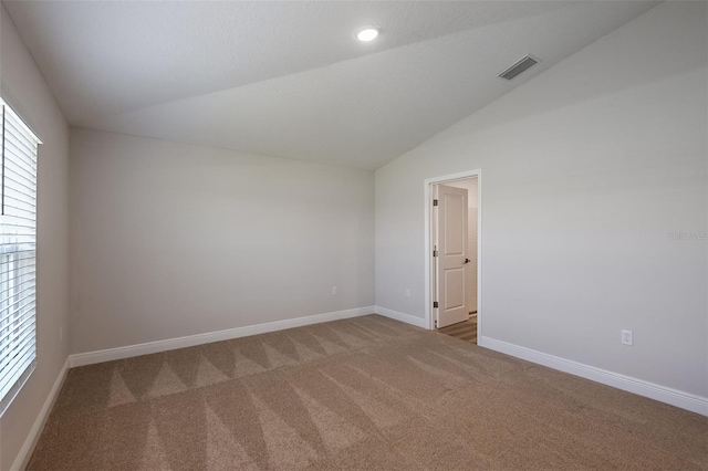 carpeted empty room with baseboards, visible vents, vaulted ceiling, and recessed lighting