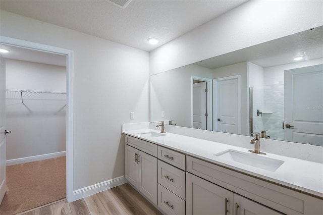 bathroom featuring double vanity, wood finished floors, a sink, and baseboards