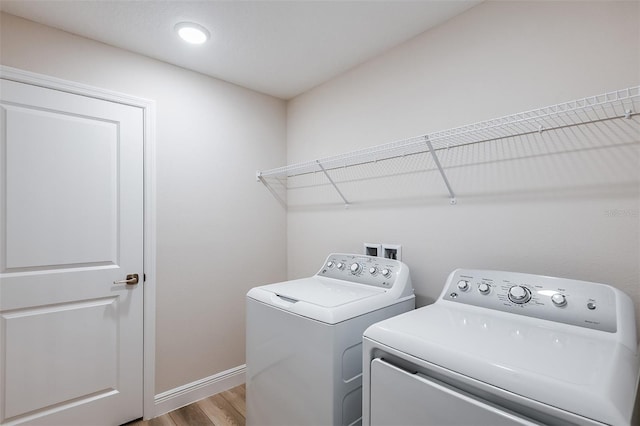 washroom featuring baseboards, laundry area, wood finished floors, and washer and dryer