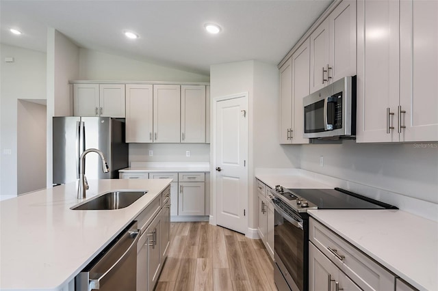 kitchen with light wood finished floors, recessed lighting, appliances with stainless steel finishes, vaulted ceiling, and a sink