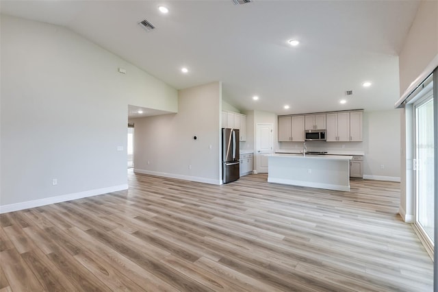 kitchen with appliances with stainless steel finishes, open floor plan, visible vents, and light wood finished floors