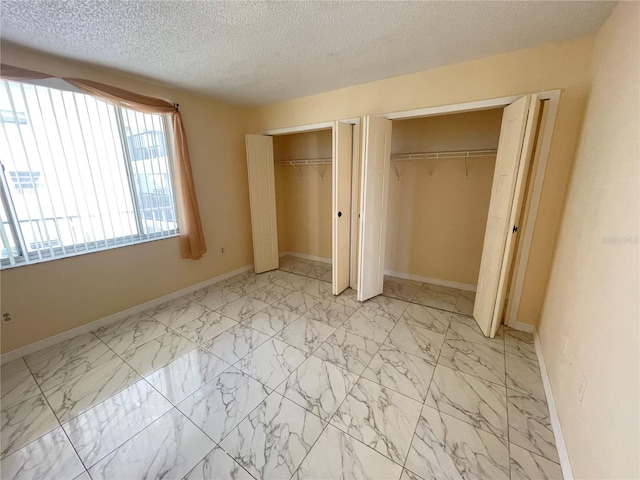 unfurnished bedroom featuring a textured ceiling and two closets