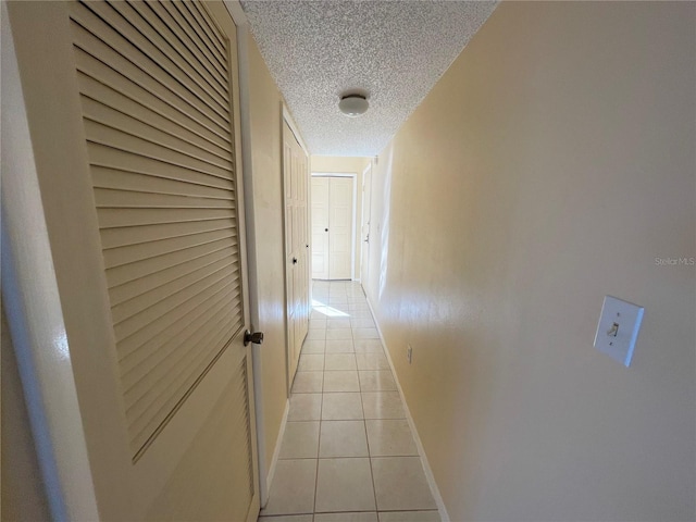 hall featuring light tile patterned floors and a textured ceiling