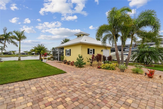 back of property featuring a yard, a water view, and a lanai