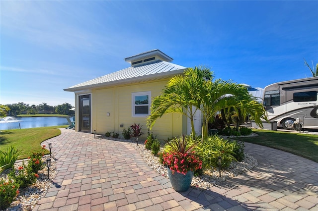 view of side of home with a water view and a lawn