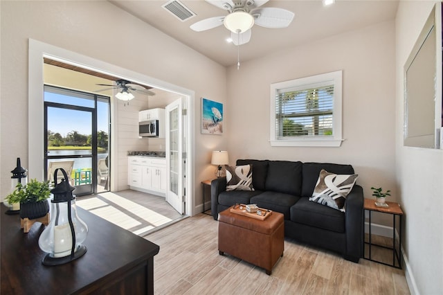 living room with plenty of natural light, ceiling fan, and light wood-type flooring