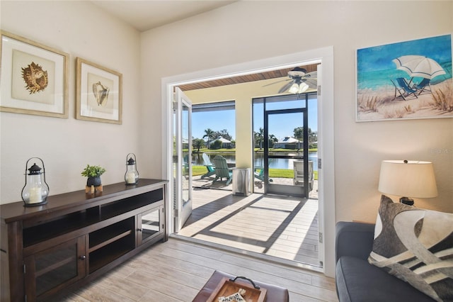 interior space with ceiling fan, a water view, and light wood-type flooring