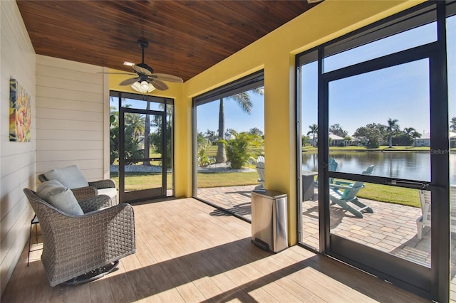 sunroom featuring ceiling fan, a water view, and wood ceiling