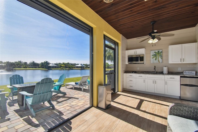 view of patio / terrace featuring sink, a water view, ceiling fan, and exterior kitchen