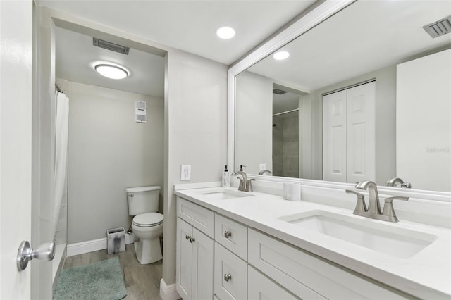 bathroom with hardwood / wood-style floors, vanity, toilet, and walk in shower