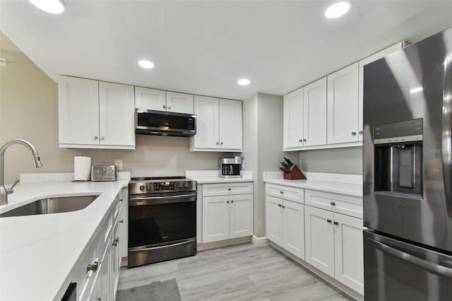 kitchen featuring appliances with stainless steel finishes, light hardwood / wood-style flooring, white cabinetry, and sink