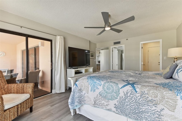 bedroom with ceiling fan, light hardwood / wood-style floors, a textured ceiling, and a closet